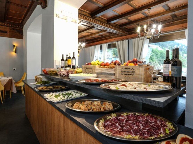 Hotel Monzoni - Rich buffet featuring local traditional fare with a wide selection of appetizers, fruits, and wine.

