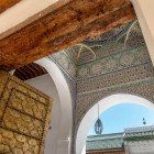 Madrasa Al-Attarine details of the door with intricately carved bronze panels and courtyard with alabaster columns