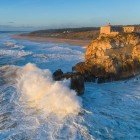 Aerial view of the Nazaré lighthouse, on the O Sitio promontory, a gigantic rock spur 318 meters high, highlighting the large waves of the Atlantic Ocean