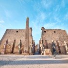 Main entrance of the Luxor Temple, highlighting the first pylon with the obelisk and statues of Ramses II