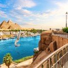 Panoramic view of the city of Aswan, highlighting the pyramids and sailboats navigating the Nile